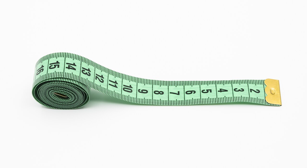 Soft tailor's measuring tape rolled on a white surface