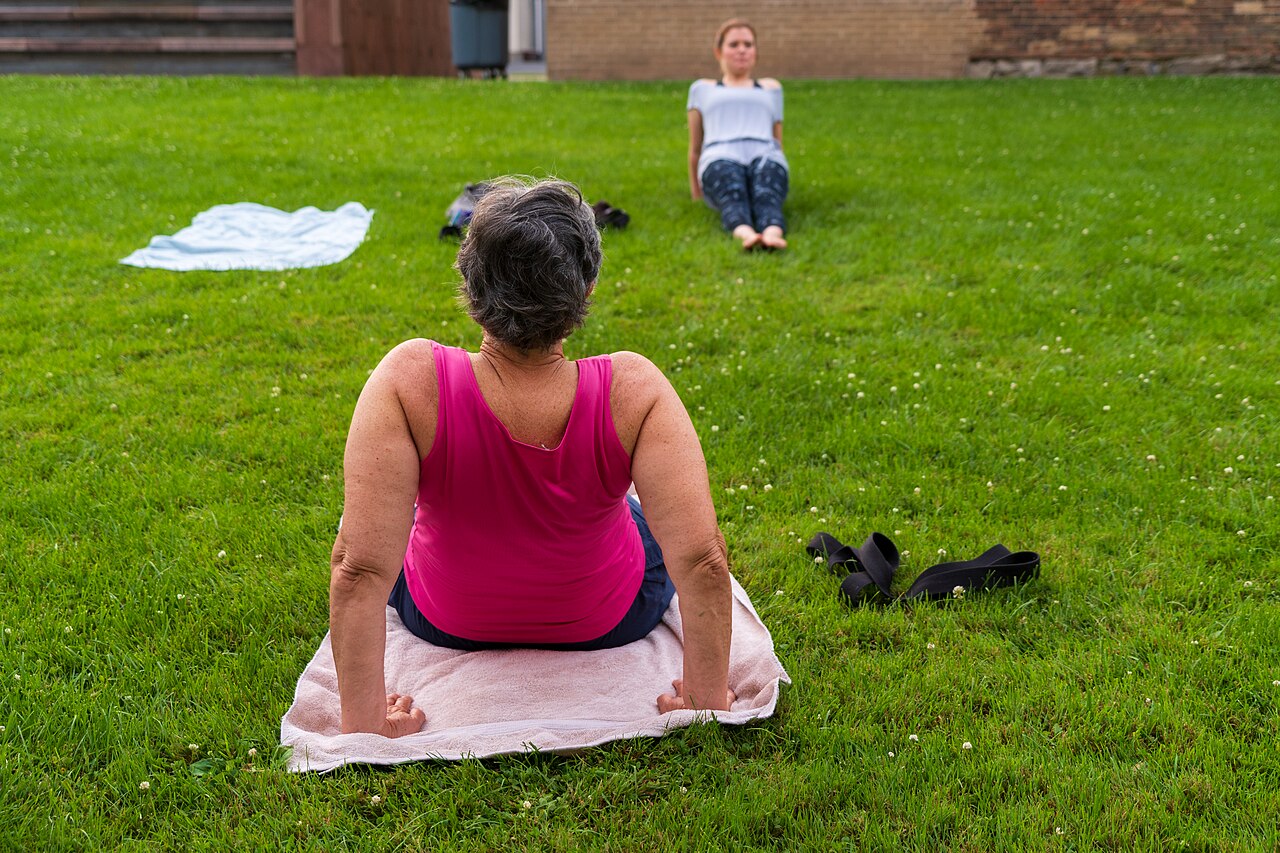 Outdoor yoga class on grass, one participant in full-length leggings